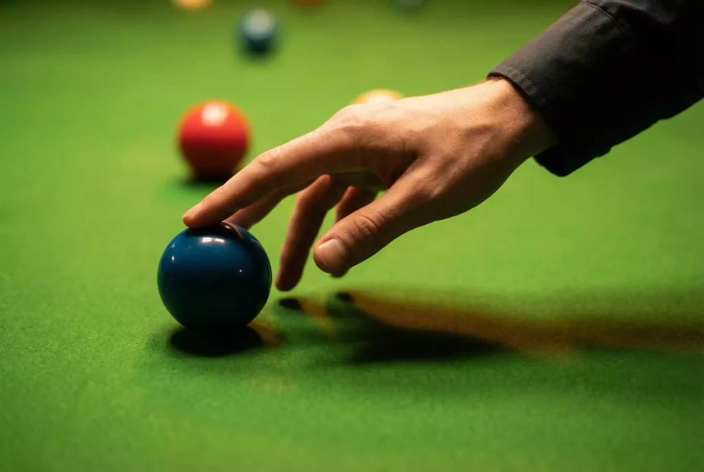 Hand greift nach einem Snooker-Ball auf dem Tisch als Symbol für den Cashout-Moment bei Sportwetten