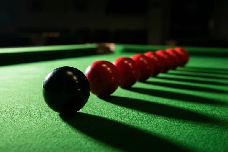 Schwarze Snooker-Kugel neben einer Reihe roter Bälle als Symbol für einen Century Break