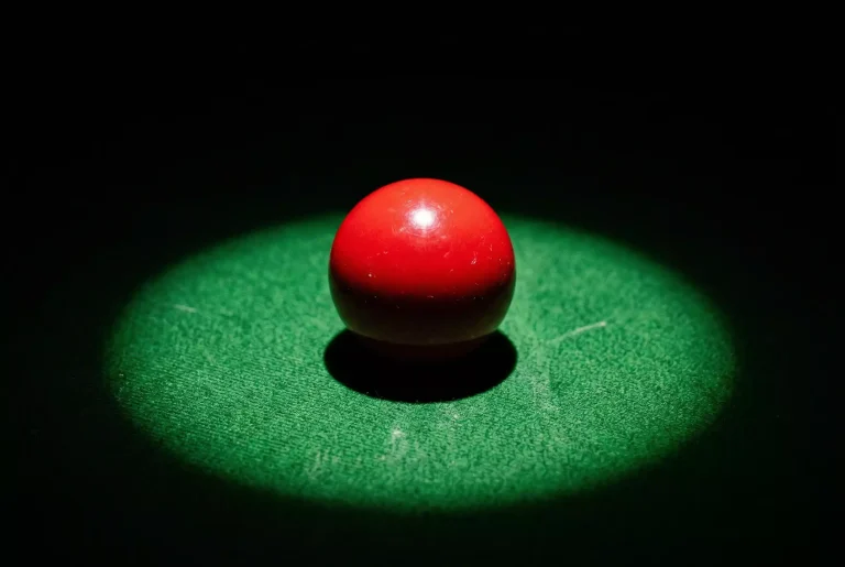 Nahaufnahme einer roten Snooker-Kugel auf dem grünen Tuch unter harter Beleuchtung als Symbol für Spielmanipulation