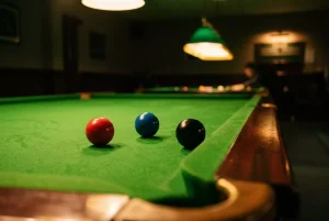 Snooker-Tisch mit Queues und farbigen Bällen unter Turnierbeleuchtung als Symbol für Quotenanalyse