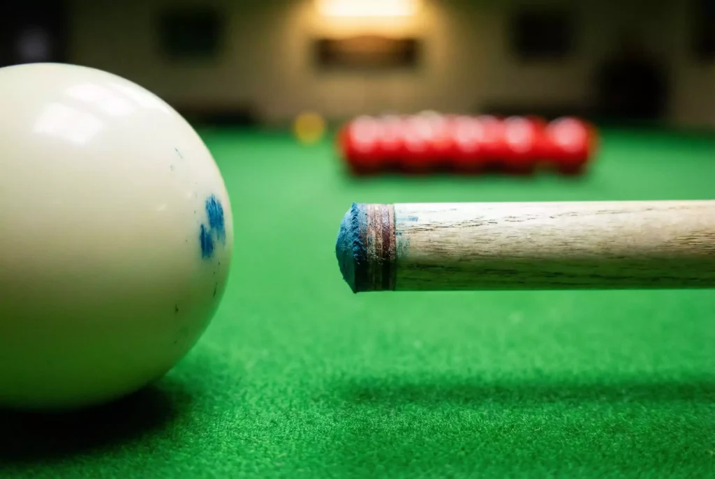 Queue-Spitze neben dem weissen Spielball auf grünem Tuch als Symbol für den Einstieg in Snooker-Wetten